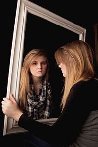 девушка грустная смотрит в зеркало