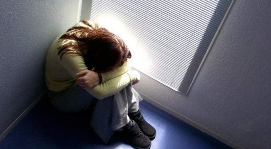 девочка обняв колени грустит